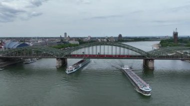 Cruise Ship Ferry Boat in Cologne City, Rhine River. Train Central Station Hbf and Hohenzollern Bridge in Background. Germany, Drone, 4k