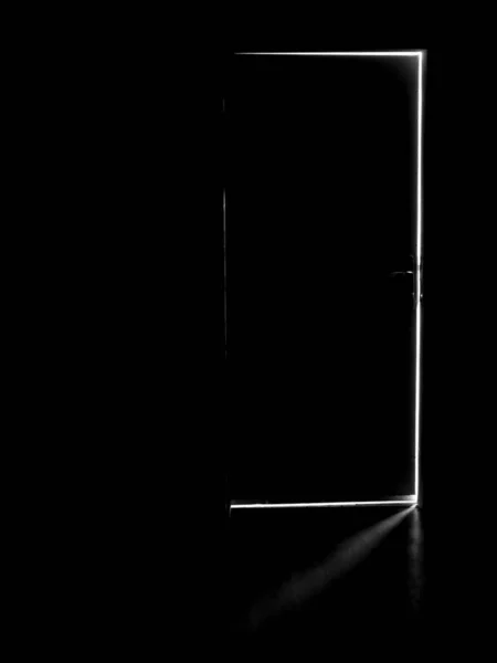 A dark door with a light behind it, light in the dark through an open door. High quality photo