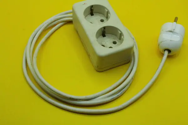 Electrical power plug on a yellow background, closeup of photo