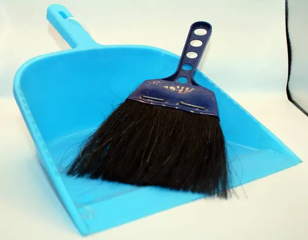 Beyaz arka planda mavi plastik kovadaki tozları temizlemek için süpürge