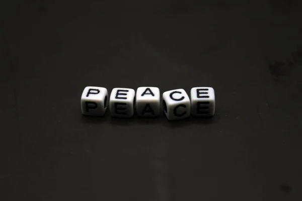 The word Peace spelled out with white box on a black background.