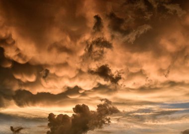Bulutlu gökyüzünü aydınlatan gün batımı.