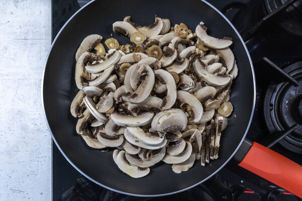 Мелко нарезанные грибы на сковороде.