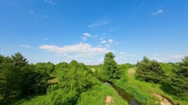 Alçak ve hızlı FPV insansız hava aracı ağaçların arasında nehrin üzerinde uçuyor..