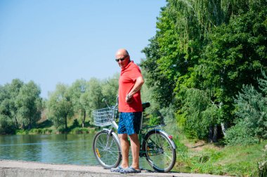 Yazın bisikletli bir adam. Dışarıda bisikleti olan bir bisikletçi. Yaz etkinliği eğlencesi ve aktif yaşam tarzı. Hafta sonu seyahati ve macera. İnsanlarla eğlence ve eğlence. Adam ve güvenilir bisikleti.