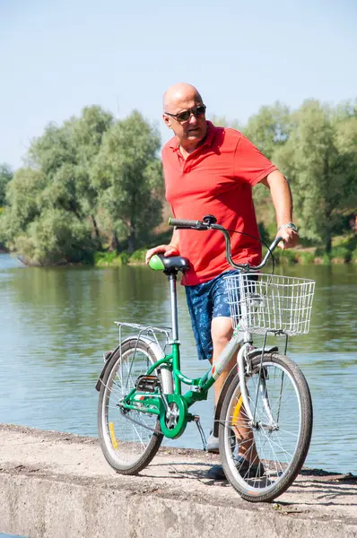 Yazın bisikletli bir adam. Dışarıda bisikleti olan bir bisikletçi. Yaz etkinliği eğlencesi ve aktif yaşam tarzı. Hafta sonu seyahati ve macera. İnsanlarla eğlence ve eğlence. Aktif adam bisiklet sürmekten hoşlanıyor..