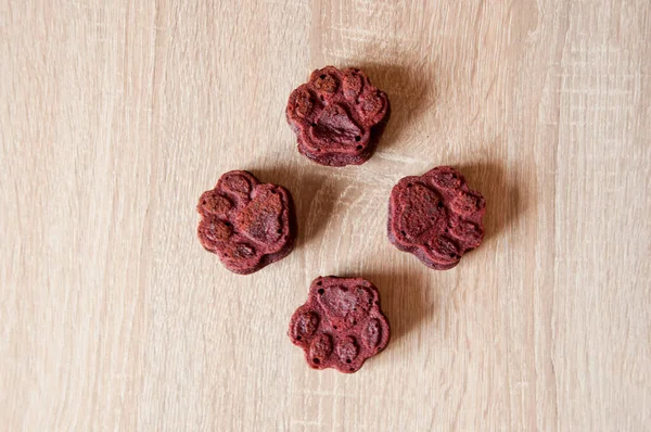 paw bakery cookie. pet cake. dog treat. pastry food for cat. appetizing dog muffins on wooden background. dog birthday. red velvet. paw shaped pet treat. homemade dog biscuit. minimalistic design.