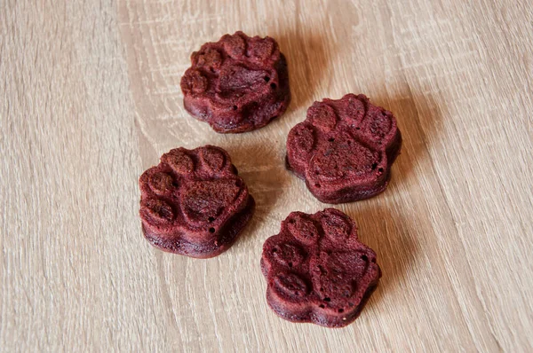 pet cake. dog treat. pastry food for cat. appetizing dog muffins on wooden background. dog birthday. red velvet. paw shaped dog treat. homemade pet biscuit. paw bakery cookie. minimalism.