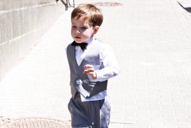 Zarif smokinli küçük bir çocuk. Smokin giymiş küçük bir çocuk. Erkek giyim bölümünde çocuk. Çocukluktaki beyefendiler için resmi kıyafet. Düğün için çocuk modası. Çocuklar için smokin ve smokin. Papyonlu çocuk zarafeti.