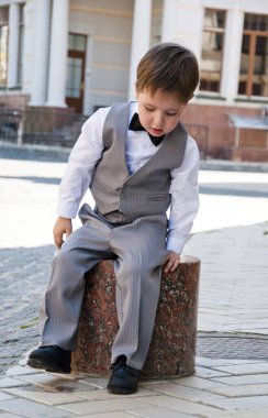 Papyonlu çocuk zarafeti. Zarif smokinli küçük bir çocuk. Smokin giymiş küçük bir çocuk. Erkek giyim bölümünde çocuk. Çocukluktaki beyefendiler için resmi kıyafet. Düğün için çocuk modası. Çocuklar için smokin ve smokin..