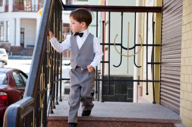 Çocukluktaki beyefendiler için resmi kıyafet. Düğün için çocuk modası. Çocuklar için smokin ve smokin. Papyonlu çocuk zarafeti. Zarif smokinli küçük bir çocuk. Smokin giymiş küçük bir çocuk. Erkek giyim bölümünde çocuk.