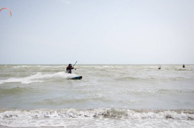 Henichesk, Ukrayna - 12 Temmuz 2021: Aktif spor. Kiteboardcu uçurtmayla uçurtma uçuruyor. Su sporu adrenalini. Uçurtma. Uçurtma sörfü antrenmanı yapan aktif bir sporcu..