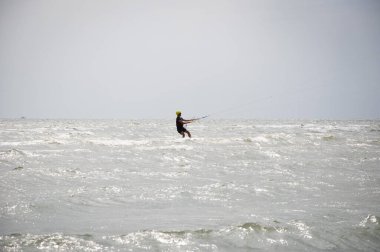 Henichesk, Ukrayna - 12 Temmuz 2021: Uçurtma. Yazın ekstrem spor ve su sporları. Yamaç paraşütü ve su kayağı. Adam uçurtma sürüyor. Deniz dalgaları üzerinde uçurtma. Serbest sörf. Yelkenli sporu.