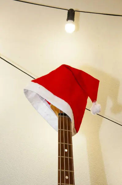 Christmas music playlist. Merry Christmas. Happy Ney Year. Xmas holiday celebration. New Year eve. Santa Claus hat on guitar. December holiday with music playlist. Decorated Xmas electric guitar.