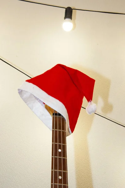 Merry Christmas. Happy Ney Year. Xmas holiday celebration. New Year eve. Santa Claus hat on guitar. December holiday with music playlist. Decorated Xmas electric guitar. Christmas music playlist.