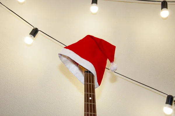 Xmas holiday celebration. New Year eve. Santa Claus hat on guitar. December holiday with music playlist. Decorated Xmas electric guitar. Christmas music playlist. Merry Christmas. Happy Ney Year.