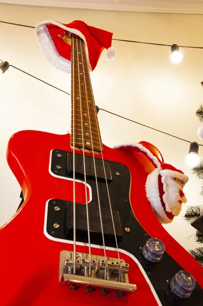 Decorated Xmas electric guitar. Christmas music playlist. Merry Christmas. Happy Ney Year. Xmas holiday celebration. New Year eve. Santa Claus hat on guitar. December holiday with music playlist.