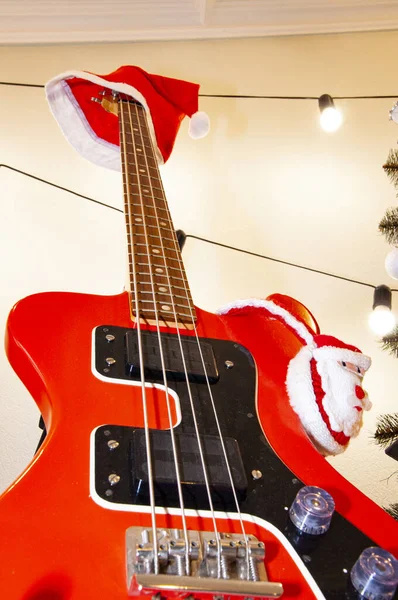 Santa Claus hat on guitar. December holiday with music playlist. Decorated Xmas electric guitar. Christmas music playlist. Merry Christmas. Happy Ney Year. Xmas holiday celebration. New Year eve.