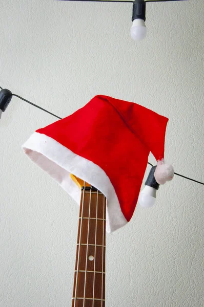 Happy Ney Year. Xmas holiday celebration. New Year eve. Santa Claus hat on guitar. December holiday with music playlist. Decorated Xmas electric guitar. Christmas music playlist. Merry Christmas.