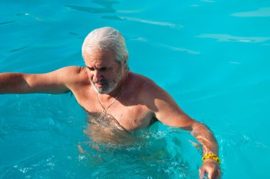 Havuzda yüzen olgun bir adam. Yaz tatili ve emeklilik. Yazın kaplıca merkezinde olgun bir adam..