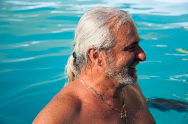 Havuzda yüzen olgun, mutlu bir adam. Yaz tatili ve emeklilik. Yazın kaplıca merkezinde olgun bir adam..