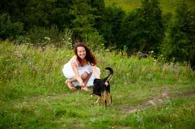 Yaz doğasının manzarası. Mutlu kız vadide köpekle oynuyor. Köpekli Karpatyalı kadın. Yeşil çimenlikteki kadın ve köpek. Dağ vadisindeki kadın ve köpek. Nefes kesici manzara..