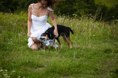 Yeşil çimenlikteki kadın ve köpek. Dağ vadisindeki kadın ve köpek. Yaz doğasının manzarası. Mutlu kız vadide köpekle oynuyor. Köpekli Karpatyalı kadın. Eğleniyorum..