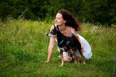 Dağ vadisindeki kadın ve köpek. Yaz doğasının manzarası. Mutlu kız vadide köpekle oynuyor. Köpekli Karpatyalı kadın. Yeşil çimenlikteki kadın ve köpek. Pankart.