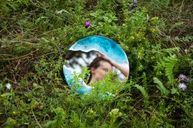 Kadınlar aynaya bakar. Yaz doğası. Aynadaki yansımadaki güzel kız. Güzellik ve süreklilik. Yeşil yaz çimlerinde yansıyan aynadaki kadın..