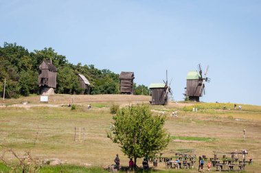 Rüzgar değirmeni. Kırsal kesimde bir yel değirmeni. Rüzgâr Çiftliği. Hollanda rüzgar gülü. Kırsal kesimdeki geleneksel Ukrayna yel değirmeni evleriyle manzara. Kırsal alanda yel değirmeni.