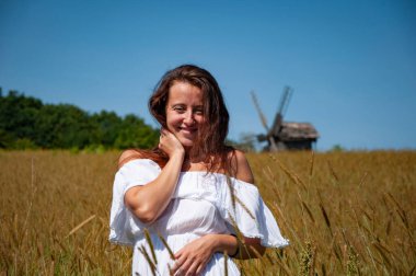 Yaz çayırı. Ukrayna buğday tarlasında beyaz elbiseli bir kadın. Ukrayna 'da çivili bir kadın. Açık havada giyinmiş yaz kadını. Kız ve kırsal doğa. Kırsal kesimden bir kadın sahada.