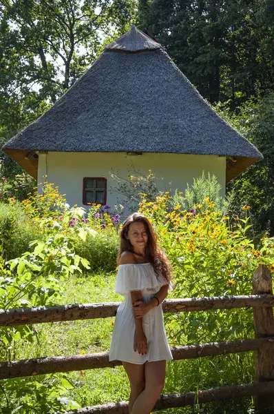 Woman in summer farm. Authentic Ukrainian architecture. Woman outdoor. Ukrainian woman in summer village cottage. Ukraine folk authentic house home. Thatched house in Ukrainian village.
