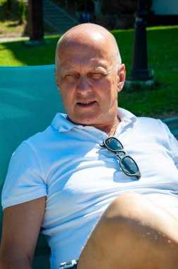 Yazın açık havada güneşlenirsin. Yaz tatili. Havuz kenarında yaz zamanı. Cesur adam dinlenme alanında güneşlenir. Yazlık tatil beldesinde. Güneş gözlüklü insan eğlencesi.