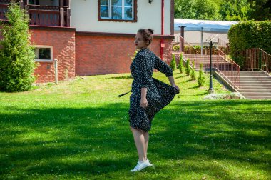 Yaz tatili ve yaz tatili. Yaz mevsimi moda tarzı. Yeşil çimlerin üzerinde dans eden yazlık elbiseli kadın. Çimlerde romantik kız dansı. Yazlık parktaki kaygısız kadın. Mutluluk.