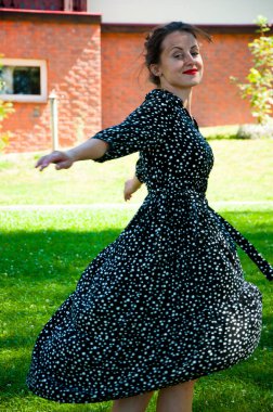 Yaz tatili ve yaz tatili. Yaz mevsimi moda tarzı. Yeşil çimlerin üzerinde dans eden yazlık elbiseli kadın. Çimlerde romantik kız dansı. Yazlık parktaki kaygısız kadın. Bronzlaşmış güzellik.