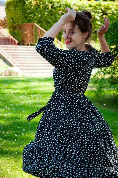 Romantic girl dance on lawn. Carefree woman in the summer park outdoor. Summer vacation and summertime. Summertime fashion style. Woman in summer dress dancing on the green grass. Flirty beauty.