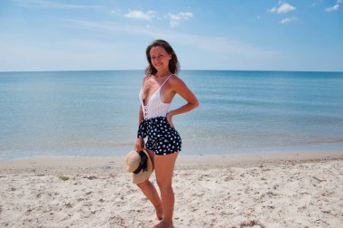 Yaz plajında güneş yanığı. Retro kızın plaj tatili. Deniz yolculuğu merkezi. Plajda yaz tatilindeki bir kadın. Mayolu hasır şapkalı yaz tatili kadını. Deniz sahilindeki Retro kadın. Havuz kenarında rahatlama.