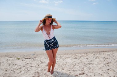 Yaz plajında güneş yanığı. Retro kızın plaj tatili. Deniz yolculuğu merkezi. Plajda yaz tatilindeki bir kadın. Mayo ve hasır şapkalı kadınların yaz tatili. Deniz sahilindeki Retro kadın. Miami.