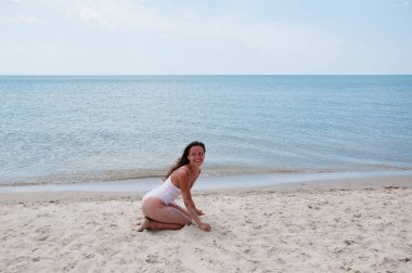 Plajda yaz tatilindeki bir kadın. Mayolu kadınların yaz tatili. Deniz kumsalındaki seksi kadın. Yaz plajında güneş yanığı. Kum kızının plaj tatili. Deniz ve kum. Eğleniyorum..