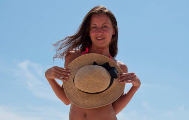 Yaz plajında güneş yanığı. Genç kızın plaj tatili. Deniz yolculuğu merkezi. Plajda yaz tatilindeki bir kadın. Mayo ve hasır şapkalı kadınların yaz tatili. Deniz kıyısındaki kadın. Cilveli kız.