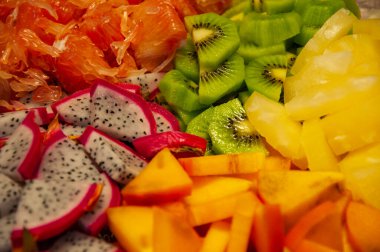 Egzotik meyve. Ananas, ejderha meyvesi, diospyros, greyfurt ve kivinin egzotik yaz meyveleri. Egzotik vitamin salatası. Tropik salata. Ada yemeği. Lüks meyve karışımı. Tropik yiyecekler. Renkli arkaplan.