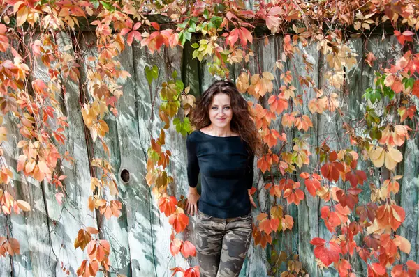 Sonbahar tarzı kıvırcık saçlı bir kız. Sonbahar kızı tarzı moda. Kadın saç bakımı. Açık havada kadın portresi. Sonbahar yaprakları ve genç bir kız. Sonbahar parkında milenyum kadını. Sonbahar portresi. Milenyum tarzı.