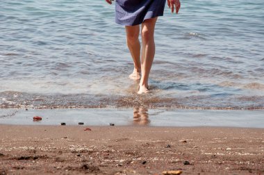 Deniz sahilinde yalınayak yürümek. Yaz tatili. Cilt bakımı. Uzay afişini kopyala. Karayipler sahilinde çıplak ayakla yürüyen bir kadın. Balayı seyahati.