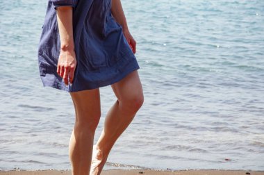 Deniz sahilinde yalınayak yürümek. Yaz tatili. Cilt bakımı. Uzay afişini kopyala. Gün batımında deniz dalgalarında bir kadının ayakları.