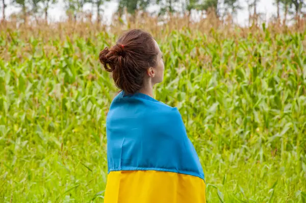 Ukrayna bayrağı. Ulusal vatansever kız. Bağımsızlık Günü. Vatanseverlik sembolü. Vatanseverlik. Ukrayna bayrağı anma günü veya 24 Ağustos. Tarlada Ukrayna bayrağıyla kaplanmış bir kız.