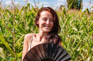 Gülümseyen yüzlü mutlu kız siyah flamenko yaz hayranı sıcak mısır tarlasında, geyşa modasında.