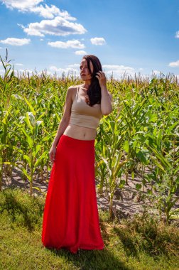 Kırsal yaşam tarzı. Genç kız, renk farkı. Kadınsı güç ve güzellik, feminizm. Genç bir kadın mavi gökyüzünün altında mısır tarlası. Doğa kaçışı. Yaz modası. Canlı kırmızı etekli İspanyol kız. Güneş yanığı.