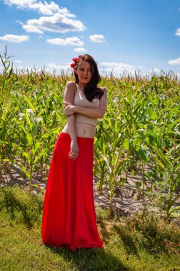 Kır manzarası. Folklorik kız. Etnik ve halk. Mısır tarlasında mavi gökyüzünün altında genç bir kadın. Flamenko dansçısı. Yaz modası. Canlı kırmızı etekli İspanyol kız ve saçlı çiçek. Masumiyet.