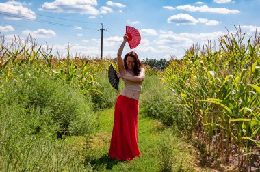 Küresel turizm. Kadınsal özgürlük. Folklorik kız seyahati. Flamenko dansçısı. Tarlada dans eden kırmızı etekli güzel bir kadın. Halk kültürü. Geleneksel dans flamenkosu. Sanatsal yaşam tarzı.