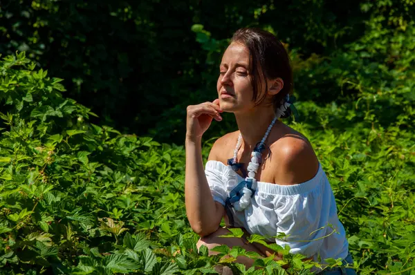 Tropik güzellik. Bitkisel ilaçlar. Rahatlama inzivası. İnci kolyeli genç İspanyol kız, yeşil beyaz. Doğa terapisi. Yeşillik ormanında oturan bir kadın. Egzotik orman.